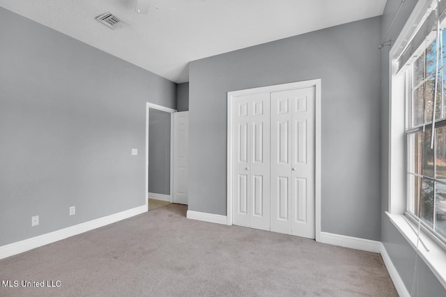 unfurnished bedroom with carpet flooring, baseboards, visible vents, and a closet