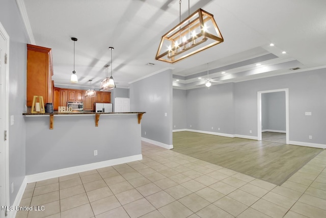 kitchen featuring fridge with ice dispenser, ornamental molding, stainless steel microwave, dark countertops, and a raised ceiling