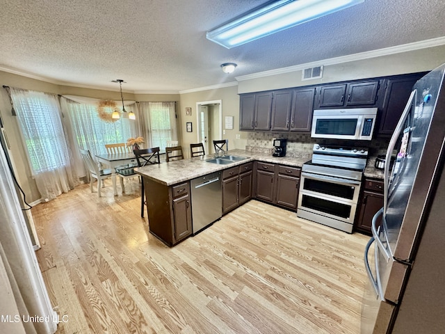 7264 Flower Creek Dr, Southaven, MS 38671 - kitchen featuring stainless steel appliances, a textured ceiling, light wood-style flooring, a peninsula, and crown molding