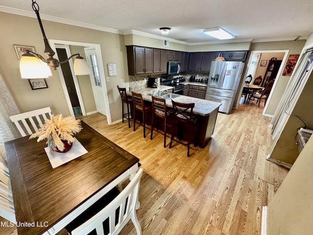 7264 Flower Creek Dr, Southaven, MS 38671 - kitchen with appliances with stainless steel finishes, a peninsula, light wood-style flooring, tasteful backsplash, and ornamental molding