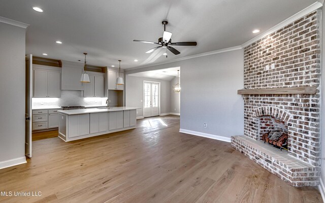 kitchen featuring white cabinets, sink, a kitchen island with sink, ceiling fan, and crown molding