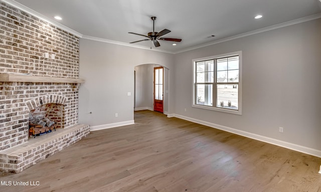 unfurnished living room with ceiling fan, ornamental molding, a fireplace, and hardwood / wood-style floors