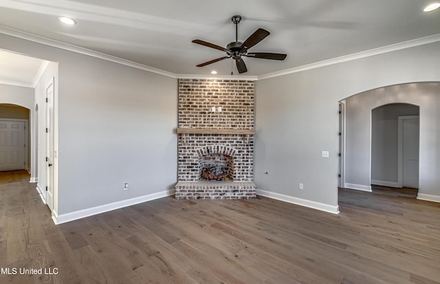 unfurnished living room featuring ceiling fan, ornamental molding, a fireplace, and hardwood / wood-style floors