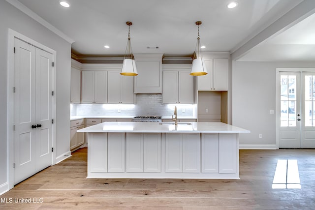 kitchen with sink, white cabinetry, and a kitchen island with sink