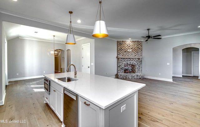 kitchen with appliances with stainless steel finishes, white cabinets, sink, pendant lighting, and an island with sink