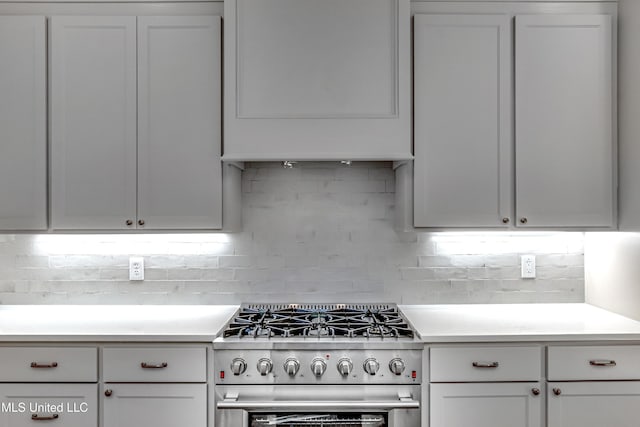 kitchen featuring backsplash, stainless steel stove, and white cabinets