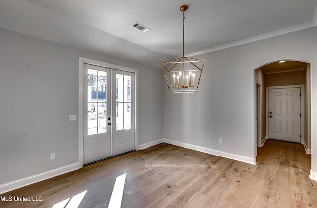 interior space with light hardwood / wood-style floors, a chandelier, crown molding, and french doors