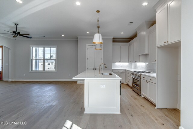 kitchen featuring white cabinetry, a kitchen island with sink, sink, pendant lighting, and high end stove