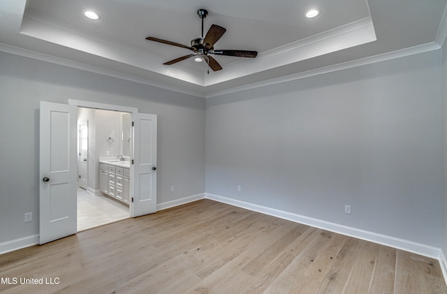 unfurnished bedroom featuring light hardwood / wood-style floors, a raised ceiling, and ceiling fan