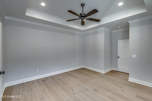 empty room featuring ceiling fan, ornamental molding, a raised ceiling, and light hardwood / wood-style flooring