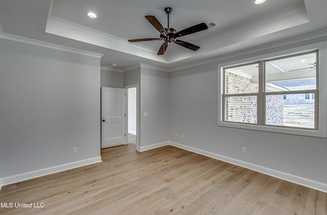 unfurnished room featuring ceiling fan, ornamental molding, light hardwood / wood-style floors, and a tray ceiling