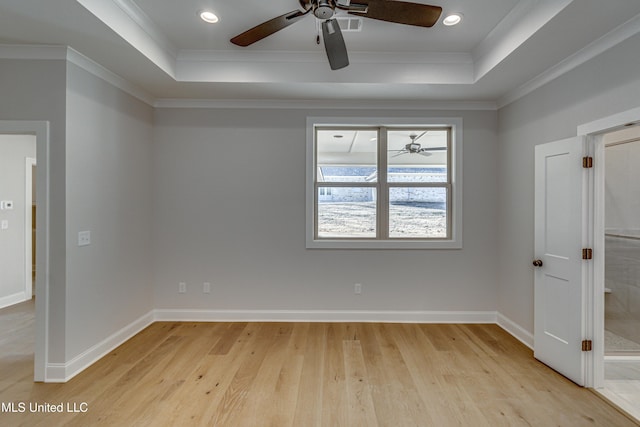 spare room featuring light hardwood / wood-style floors, a tray ceiling, and ornamental molding