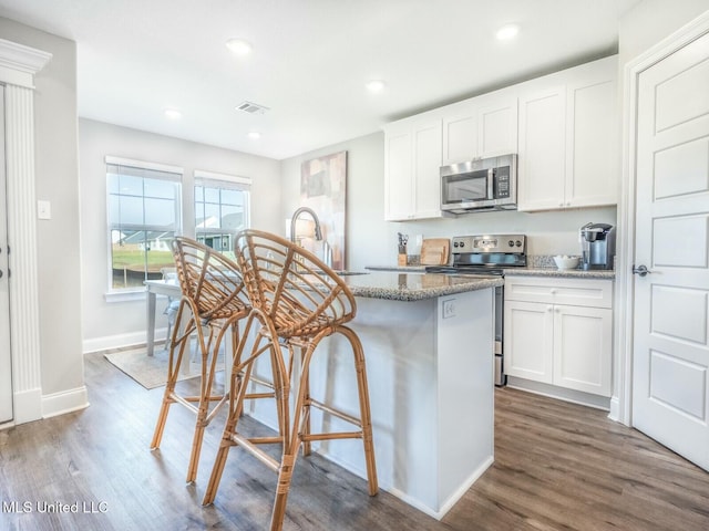 kitchen with light stone countertops, white cabinetry, stainless steel appliances, and a sink