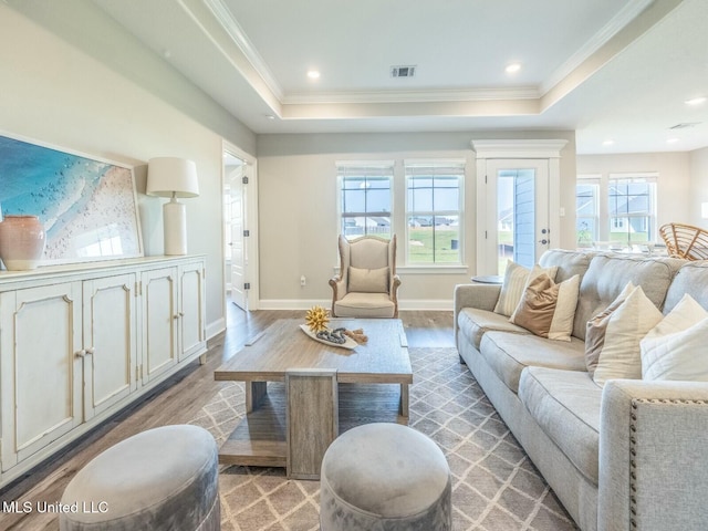 living room featuring a tray ceiling, visible vents, and light wood-style flooring