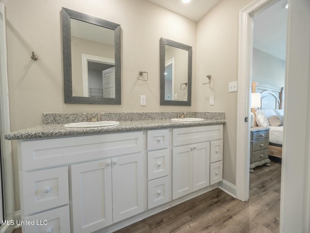ensuite bathroom featuring wood finished floors, double vanity, a sink, and ensuite bathroom