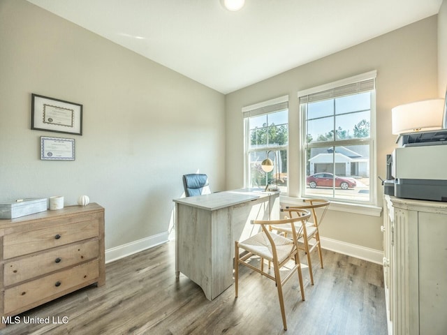 home office featuring baseboards, vaulted ceiling, and light wood-style floors