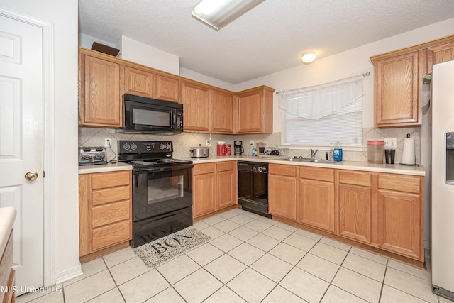 kitchen featuring sink, light tile patterned floors, black appliances, and a textured ceiling