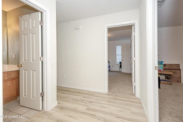 hallway featuring light carpet and a textured ceiling