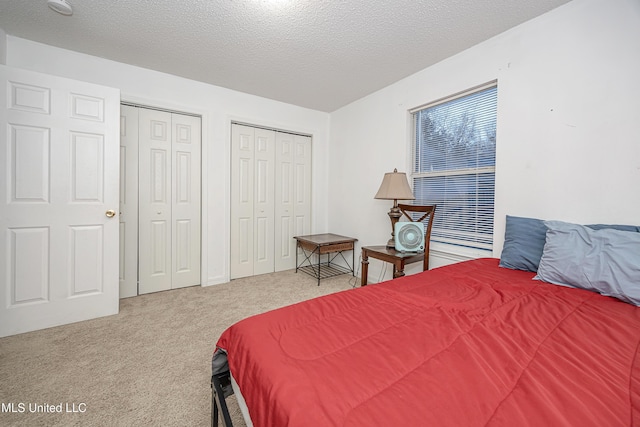 bedroom featuring carpet, a textured ceiling, and two closets