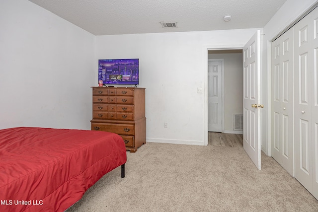 bedroom with light carpet, a textured ceiling, and a closet