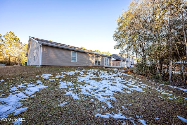 snow covered back of property featuring a wooden deck