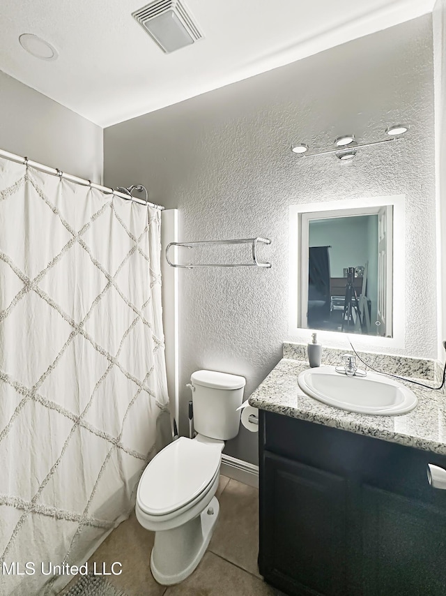full bathroom with visible vents, tile patterned flooring, a textured wall, vanity, and toilet