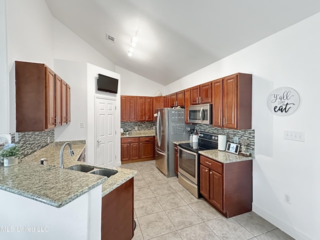 kitchen featuring light stone countertops, a sink, stainless steel appliances, a peninsula, and tasteful backsplash
