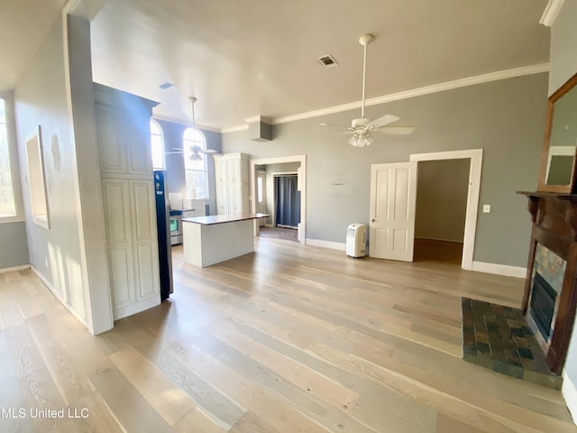 unfurnished living room featuring a stone fireplace, a wealth of natural light, light hardwood / wood-style floors, and ceiling fan