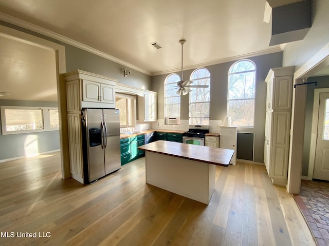 kitchen with wooden counters, appliances with stainless steel finishes, a center island, ornamental molding, and light wood-type flooring