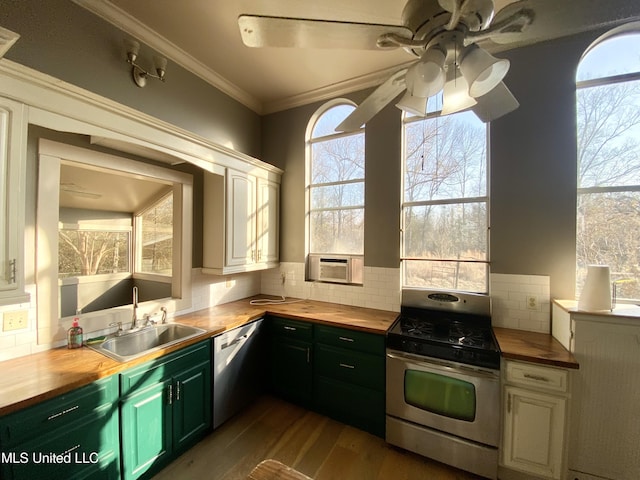 kitchen with butcher block counters, sink, tasteful backsplash, ornamental molding, and stainless steel appliances