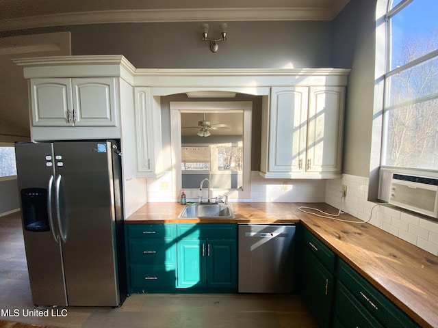 kitchen featuring sink, butcher block countertops, white cabinets, stainless steel appliances, and backsplash