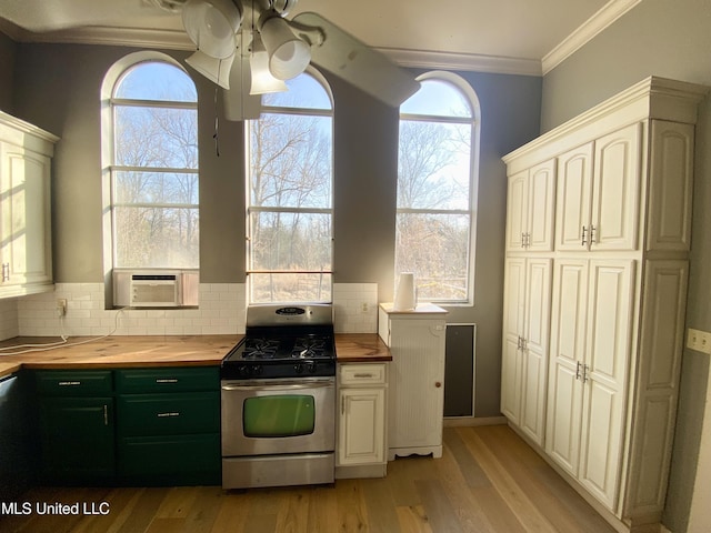 kitchen with gas range, wood counters, crown molding, and tasteful backsplash