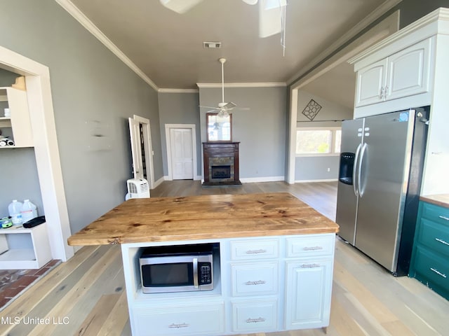 kitchen with wooden counters, appliances with stainless steel finishes, ornamental molding, white cabinets, and light wood-type flooring