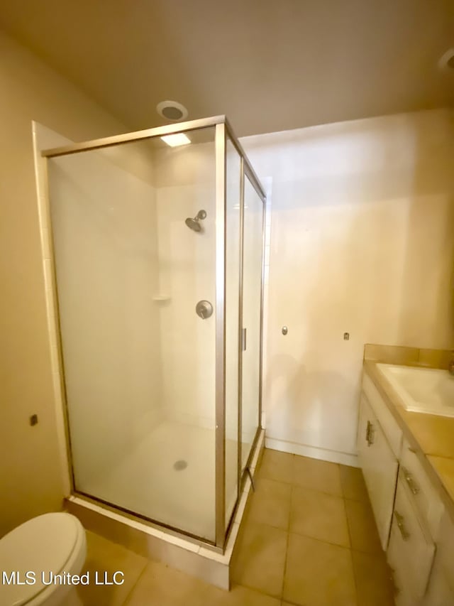 bathroom with tile patterned flooring, toilet, vanity, and a shower with shower door