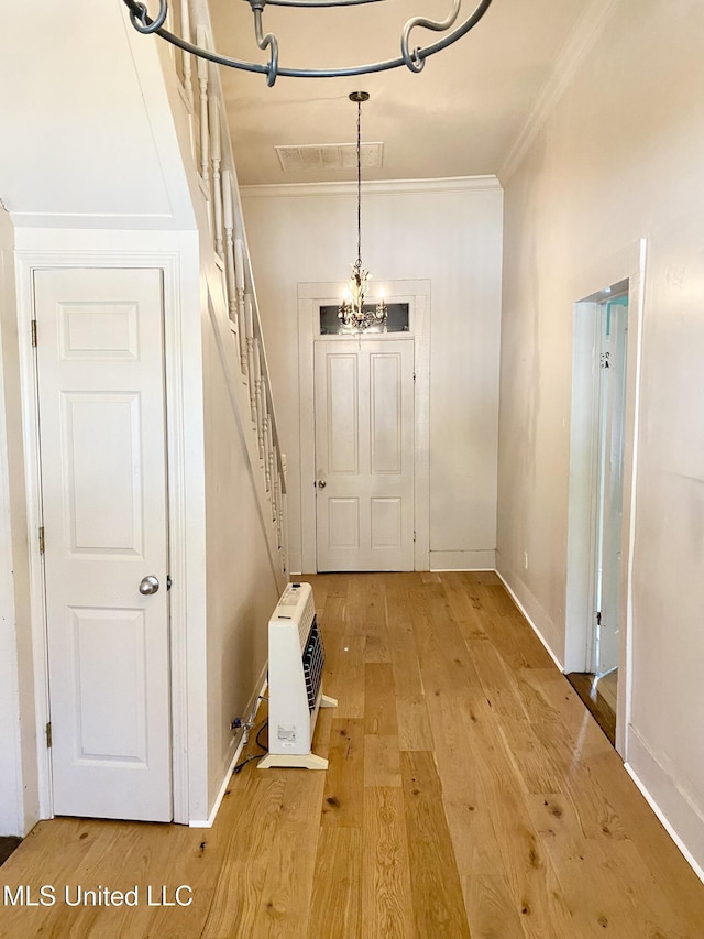 interior space featuring crown molding, a chandelier, light hardwood / wood-style floors, and heating unit