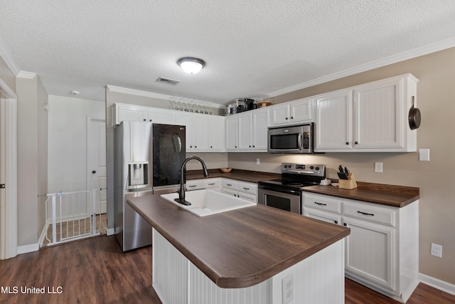 kitchen featuring stainless steel appliances, a sink, dark wood-type flooring, white cabinets, and a textured ceiling