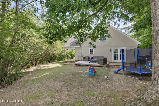 back of house featuring a trampoline, french doors, a deck, cooling unit, and an outdoor hangout area