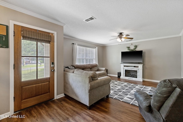 living area featuring ornamental molding, dark wood finished floors, ceiling fan, baseboards, and a textured ceiling