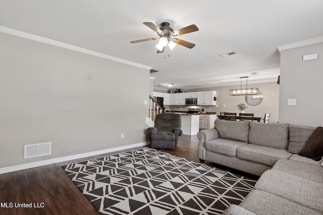 living area featuring wood finished floors, crown molding, a ceiling fan, baseboards, and a chandelier