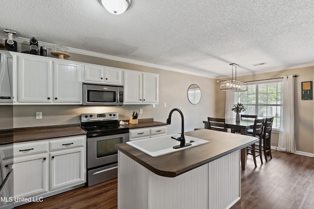 kitchen with appliances with stainless steel finishes, a textured ceiling, a sink, dark wood finished floors, and white cabinets