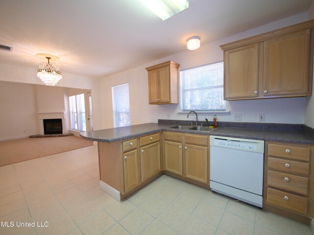 kitchen featuring dark countertops, open floor plan, white dishwasher, a sink, and a peninsula