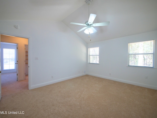 empty room featuring plenty of natural light, vaulted ceiling, and light colored carpet