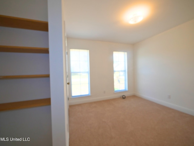 carpeted empty room featuring baseboards