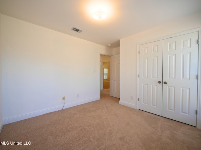 unfurnished bedroom featuring baseboards, visible vents, a closet, and light colored carpet