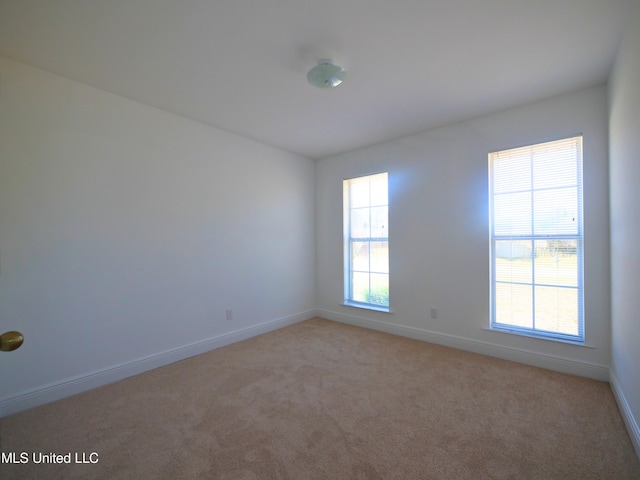 unfurnished room featuring light carpet and baseboards