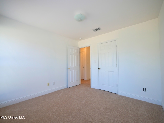 unfurnished bedroom featuring baseboards, visible vents, and light colored carpet