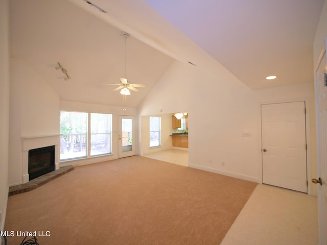 unfurnished living room featuring baseboards, a ceiling fan, a glass covered fireplace, light colored carpet, and high vaulted ceiling