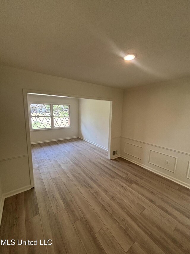747 Cumberland Cv, Southaven, MS 38671 - spare room with visible vents, a decorative wall, wood finished floors, and wainscoting