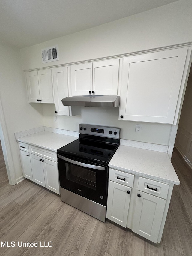 747 Cumberland Cv, Southaven, MS 38671 - kitchen with white cabinetry, under cabinet range hood, electric stove, and light wood-style flooring