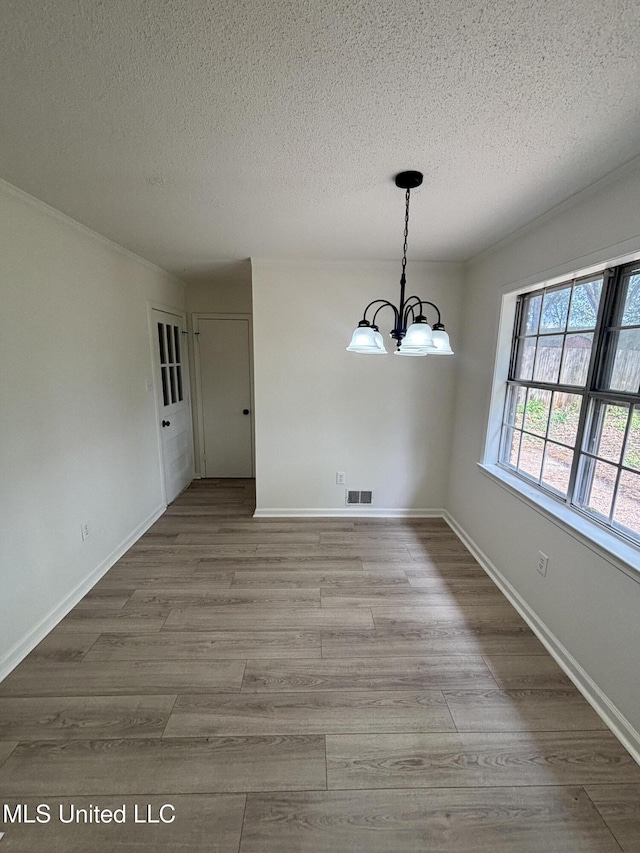 747 Cumberland Cv, Southaven, MS 38671 - unfurnished dining area featuring a textured ceiling, visible vents, wood finished floors, and an inviting chandelier